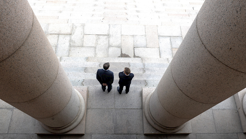 Två personer fotograferade uppifrån högst upp på parlamentsbyggnadens trappor