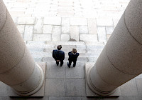 Two people photographed from above at the top of the steps of the parliament building