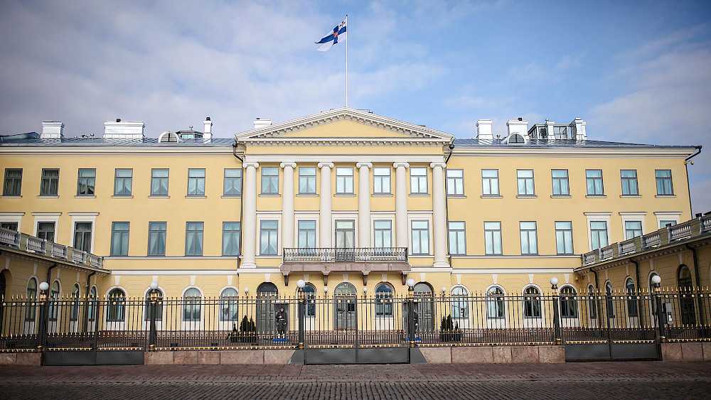 Valokuva Helsingin presidentinlinnasta, jossa Suomen lippu liehuu sen yläpuolella.