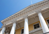 Närbild av statsrådets slott. Bilden visar massiva pelare och takdekorationer. Himlen är blå.