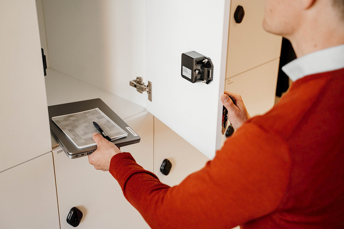 A photo showing a person putting a computer in a storage cabinet from the back.