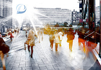 A busy city street with people walking and buildings in the background. The picture was taken from a low angle looking up at the buildings. People are out of focus, which suggests movement. The picture has a warm, golden tone, and the sun is shining brightly in the background. The building on the left has a blue logo with a white 'D'.